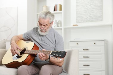 Rahatlatıcı hobi. Son sınıf öğrencisi evdeki kanepede gitar çalıyor.