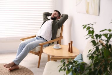 Yakışıklı adam evde koltukta dinleniyor.