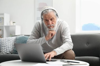 Üst düzey bir adam internette bilgisayarla kapalı bir masada öğreniyor. Kendi kendine çalışma.