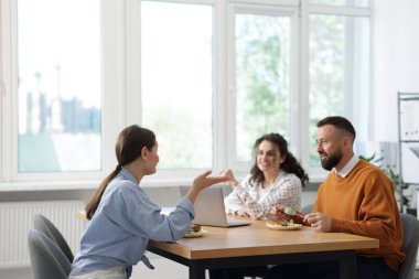 İş arkadaşları ofiste yemek yiyor ve sohbet ediyorlar.