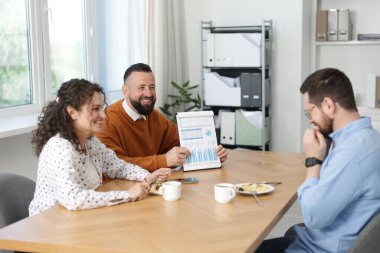 İş arkadaşları yemek yiyor ve ofiste öğle arasında iş tartışıyorlar.