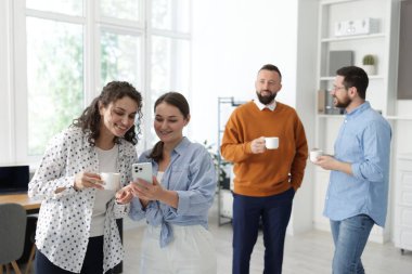 Ofiste kahve molası sırasında iş arkadaşları sohbet ediyor.