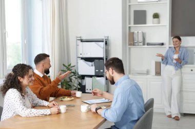 İş arkadaşları ofiste yemek yiyor ve sohbet ediyorlar.