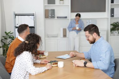 İş arkadaşları ofiste yemek yiyor ve sohbet ediyorlar.