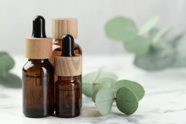 Gerekli yağ ve okaliptüs şişeleri beyaz mermer masa üzerinde, yakın çekim