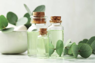 Önemli yağ şişeleri, okaliptüs yaprakları, beyaz mermer masa üzerinde havan ve tokmak, yakın çekim