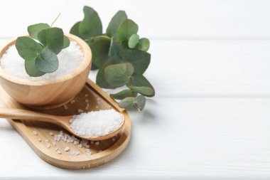 Deniz tuzu ve okaliptüs dalları beyaz ahşap masada, yakın plan. Metin için boşluk