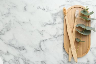 Bambu diş fırçaları ve okaliptüs dalları beyaz mermer masa, üst manzara. Metin için boşluk