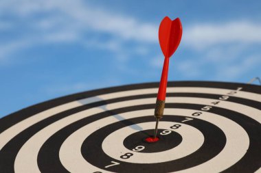 Hedef alınıyor. Mavi gökyüzüne karşı oklu dart tahtası, yakın plan.