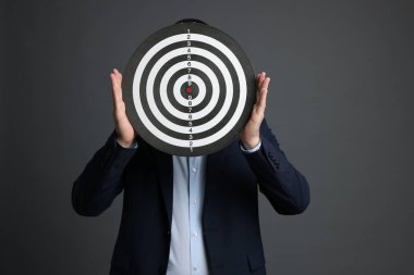 Hedef alınıyor. Gri arka planda dart tahtası olan adam.