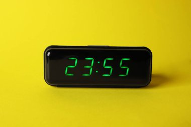 Sarı arkaplanda 23: 55 'i gösteren dijital alarm saati.