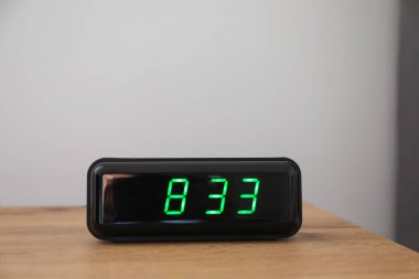 Dijital alarm saati, saat 8: 33 'ü gösteriyor. Yatağın başucundaki masada, ışık arkaplanı, metin için boşluk.