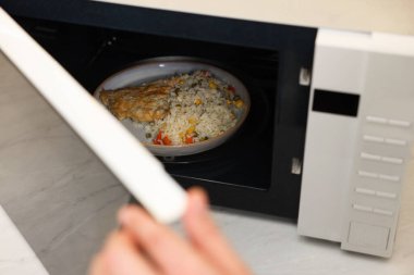 Yemek tabağını mikrodalgaya koyan adam, yakın plan.