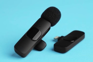 Lavalier mikrofon ve açık mavi arkaplanda kablosuz alıcı, yakın plan