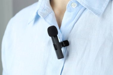 Gömleğine mikrofon takmış bir adam, yakın plan.