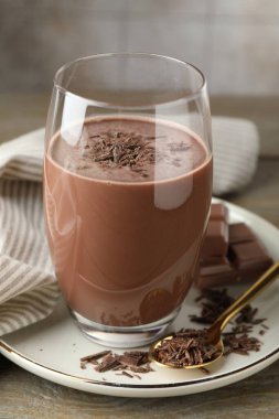 Lezzetli çikolatalı süt, ahşap masa üzerinde talaş ve parçalar, yakın plan.