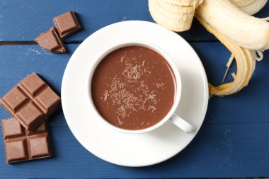 Lezzetli çikolatalı süt, parçalar ve muz mavi ahşap masada, düz uzanmış