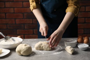 Açık gri masada hamur kesen kadın, yakın plan.