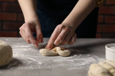 Açık gri masada simit yapan kadın, yakın plan.