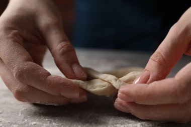 Açık gri masada simit yapan kadın, yakın plan.
