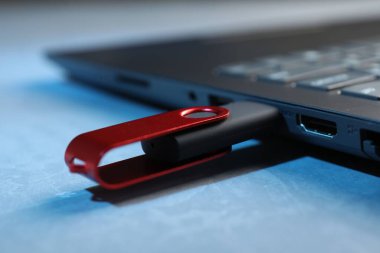 Mavi desenli masadaki dizüstü bilgisayara bağlı Usb flash diski, yakın plan