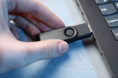 Gri desenli masadaki dizüstü bilgisayara bir kadın yerleştiriyor. Yakın plan.