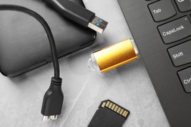 Dizüstü bilgisayara, SD bellek kartına ve gri desenli tablodaki harici sabit diske bağlı flaş bellek, düz konum