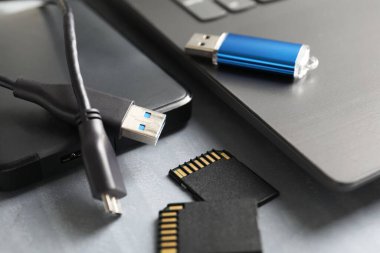 Flaş bellek, SD hafıza kartları, harici sabit disk ve dizüstü bilgisayar gri masada, yakın plan