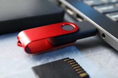 Dizüstü bilgisayara, SD hafıza kartına ve gri desenli tablodaki harici sabit diske bağlı flaş bellek.