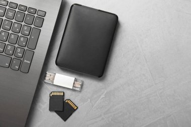 Flaş bellek, SD hafıza kartları, harici hard disk ve gri desenli sehpada dizüstü bilgisayar, düz konum. Metin için boşluk
