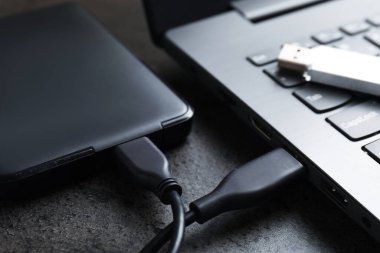 USB flash disk, kablo ve dizüstü bilgisayarlı sabit disk koyu gri masa, yakın plan
