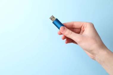 Flaş belleği açık mavi arka planda tutan kadın, yakın plan. Metin için boşluk