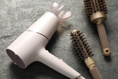 Gri dokulu arka planda farklı saç şekillendirme araçları, yakın plan