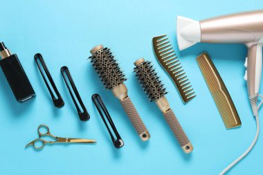 Açık mavi arka planda farklı saç şekillendirme araçları, düz yatış
