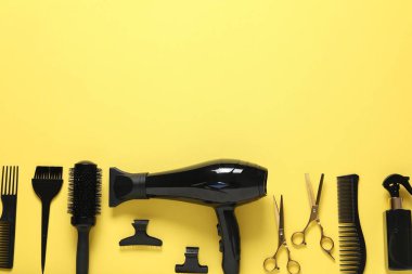 Sarı arka planda farklı saç şekillendirme araçları, düz yatış. Metin için boşluk