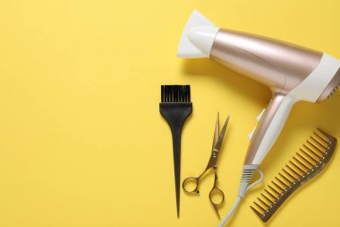 Sarı arka planda farklı saç şekillendirme araçları, düz yatış. Metin için boşluk