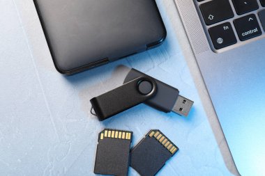 Flaş bellek, SD hafıza kartları, harici hard disk ve dizüstü bilgisayar açık gri tabloda, düz konum
