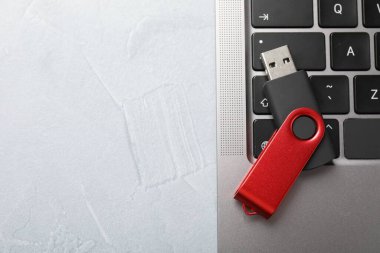 Modern flaş bellek ve laptop açık gri masada, üst görünümde. Metin için boşluk