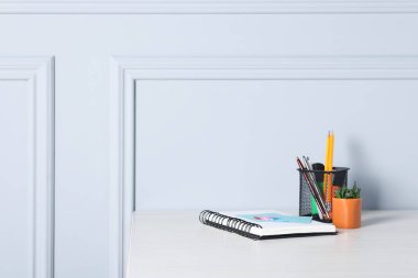 Işık duvarının yanındaki ofis masasında farklı kırtasiye ve çiçek dekoru, metin için yer