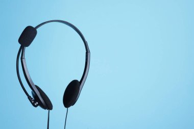 Açık mavi arkaplanda mikrofonlu kulaklık, metin için boşluk