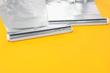 Turuncu arka planda alüminyum folyo ruloları. Metin için boşluk