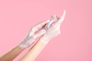 Açık pembe arka planda ellerini sabunla yıkayan kadın, yakın plan.