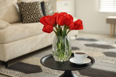 Vazodaki güzel kırmızı laleler ve içerideki masada çay, metin için yer.