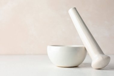 Beyaz masaya seramik havan topu ve tokmak, yakın plan. Metin için boşluk