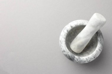 Açık gri zemin üzerinde mermer harç ve tokmak, üst manzara. Metin için boşluk