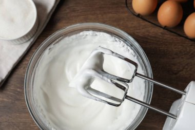 Çırpılmış çırpılmış çırpılmış krema ve ahşap masa malzemeleriyle el çırpma makinesi.