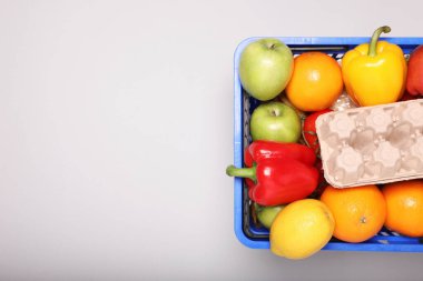 Işık arka planda ürünlerle dolu plastik alışveriş sepeti, üst manzara. Metin için boşluk