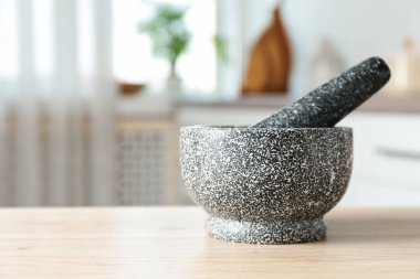 Mutfaktaki ahşap masada taş havan ve tokmak, yakın plan. Metin için boşluk