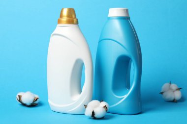 Bir şişe yumuşatıcı ve açık mavi arka planda pamuk çiçekleri.