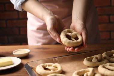 Ahşap masadaki pişirilmemiş krakerin üzerine yakın plan kraker koyan kadın.